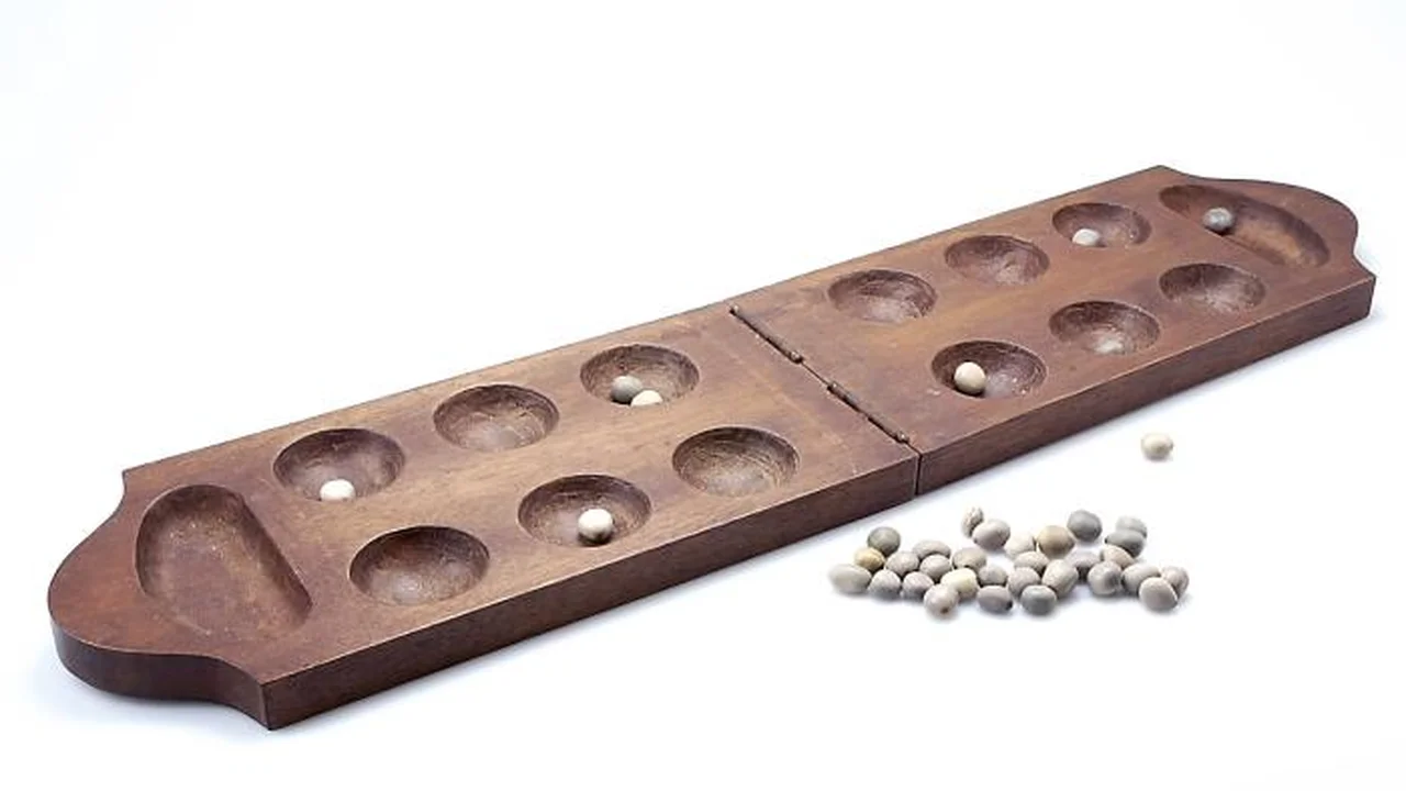 A carved folding hardwood Ba board featuring twelve round cups, two end store pits, and polished grey nickernut seeds.