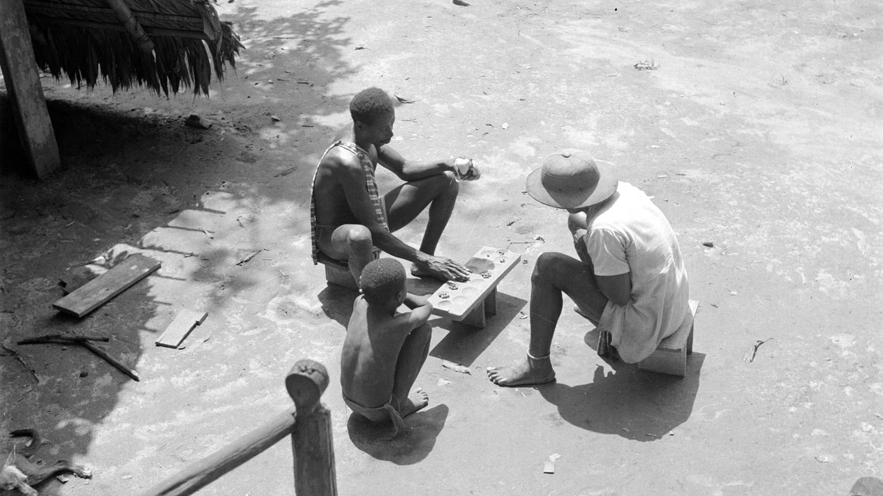 High angle view of players distributing seeds across the hollowed cups of the Ba board during a tactical match.