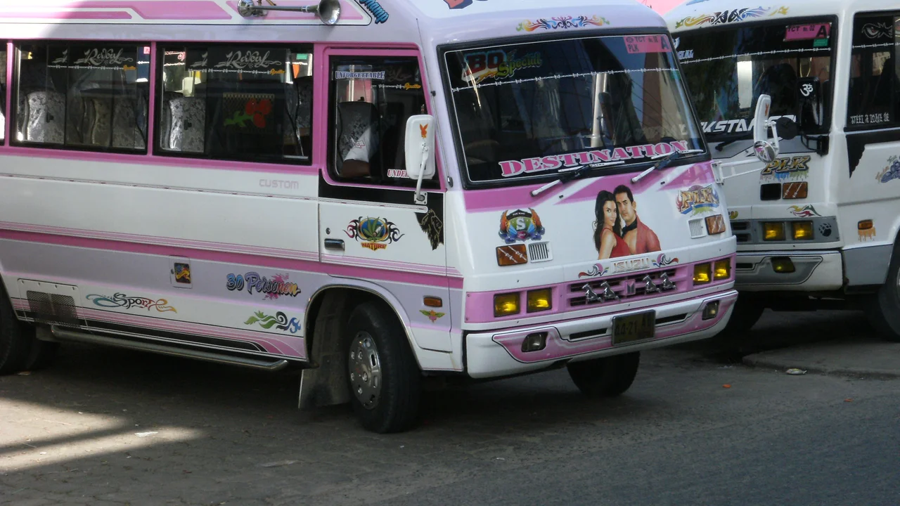 Close-up perspective of customized minibuses featuring painted route names and distinct graphic liveries.