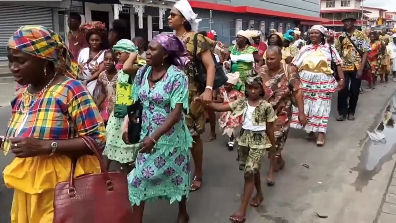 Surinamese women dressed in elaborate cotton koto gowns and folded angisa headwraps during Keti Koti festivities.