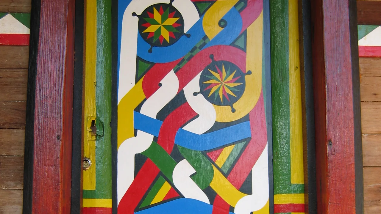 Intricately carved and brightly painted Tembe door panel displaying interlocking geometric bands and star motifs.