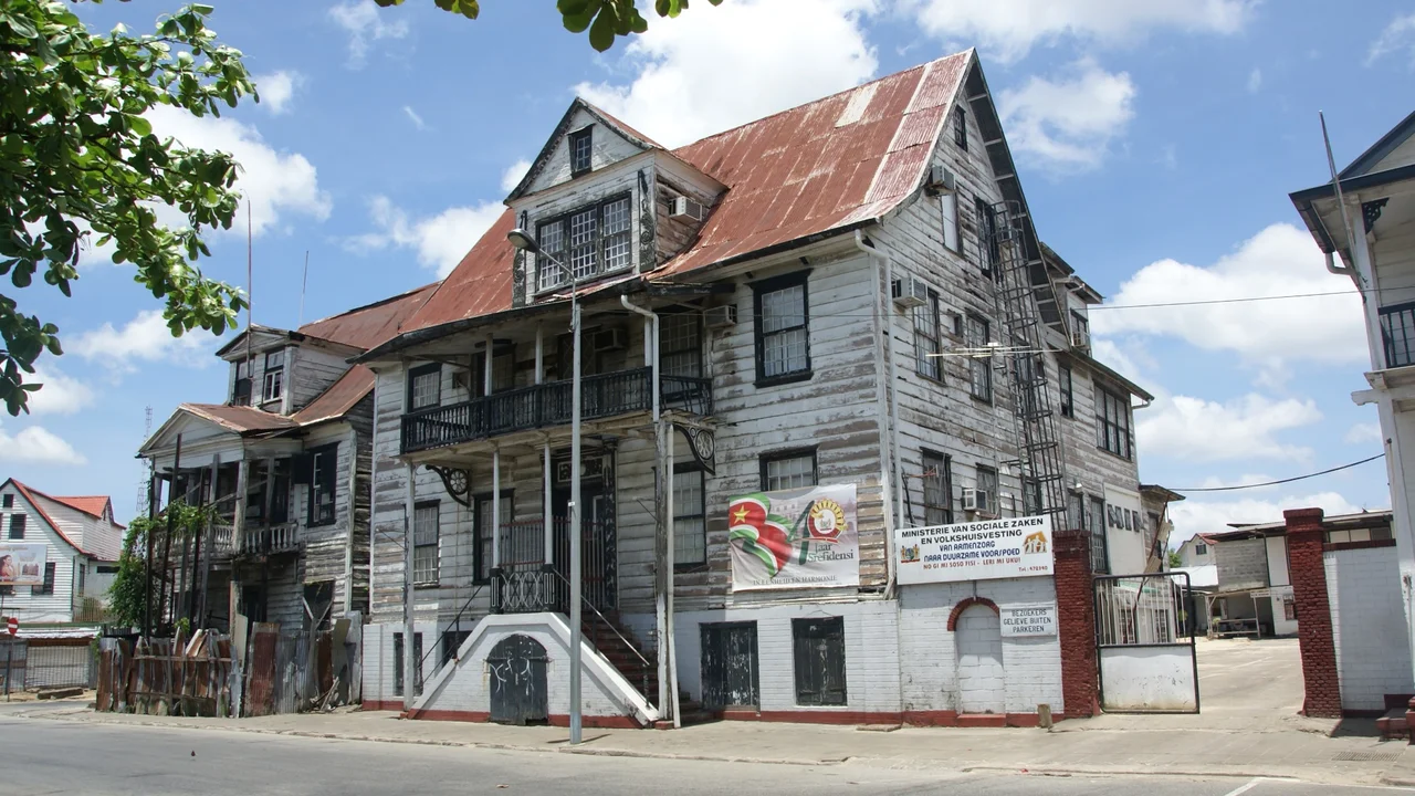 Preserved white timber colonial mansions with green louvered shutters along Waterkant in Paramaribo.