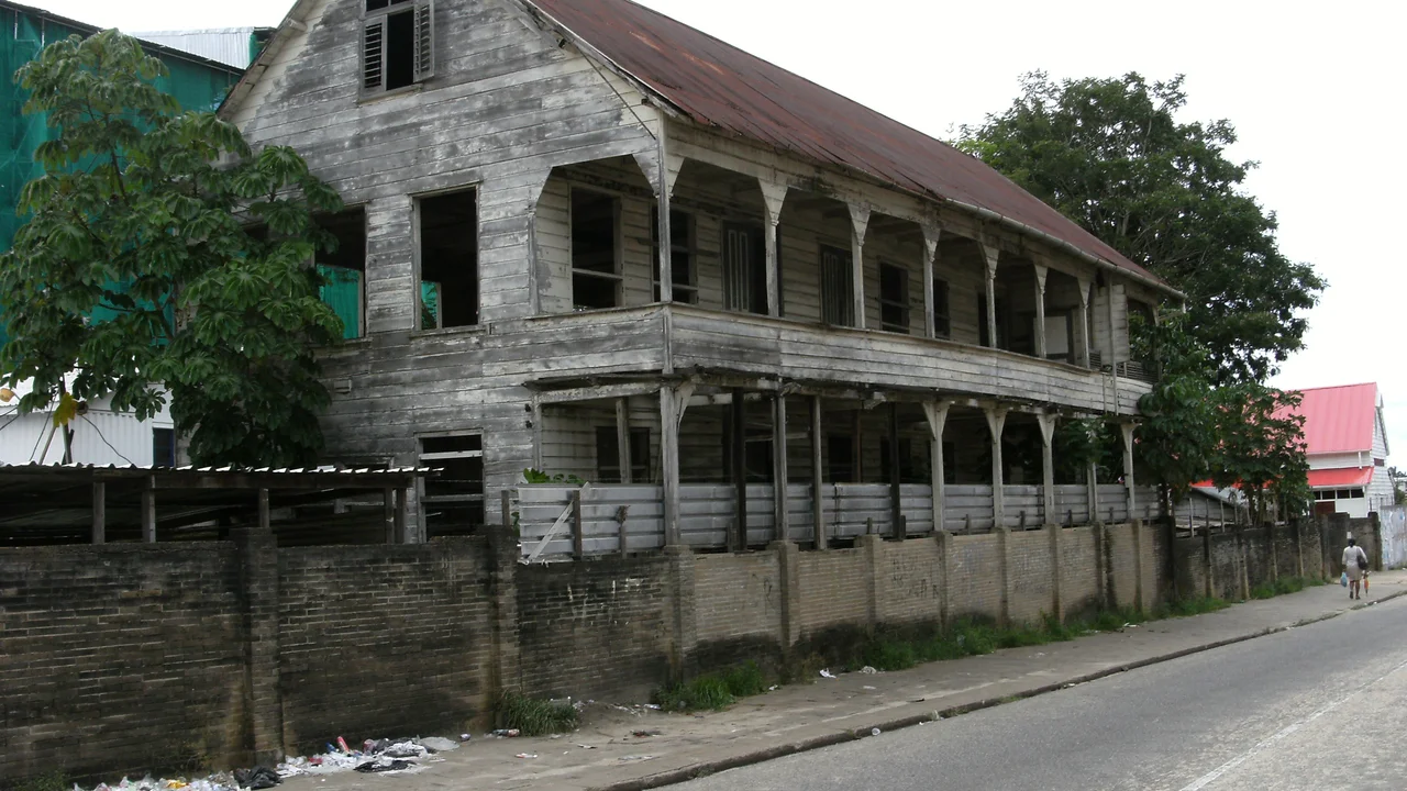 Weathered historic wooden residence showing peeling paint, exposed timber joinery, and structural conservation needs.