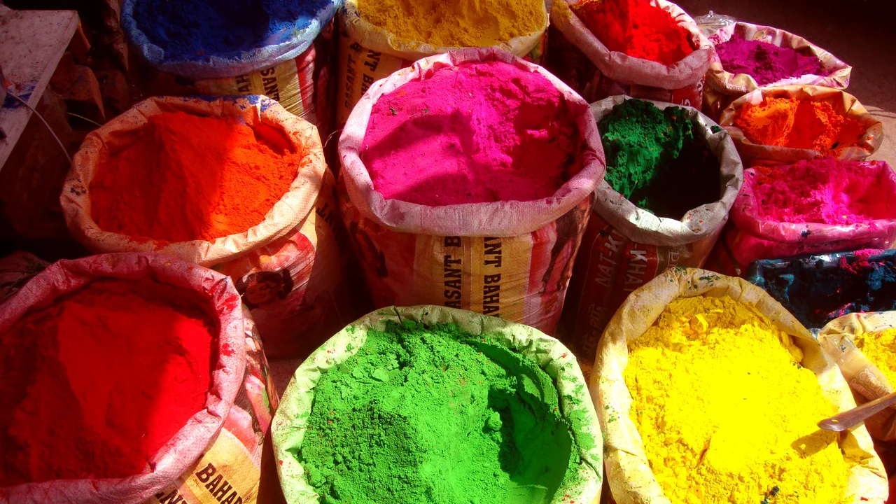 Heaps of vibrant red, green, yellow, and blue dry powder prepared for distribution during Phagwa.