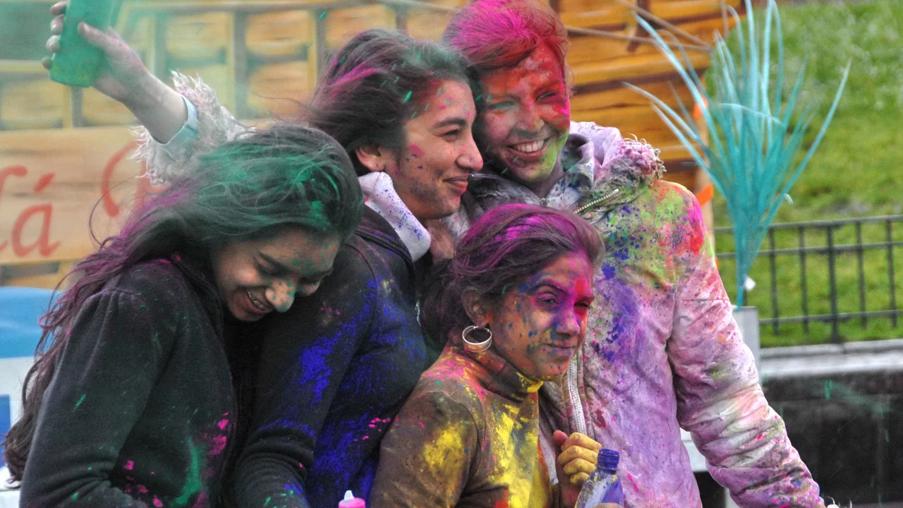 Young celebrants covered in bright red, yellow, and violet Phagwa powders during festive spring celebrations.