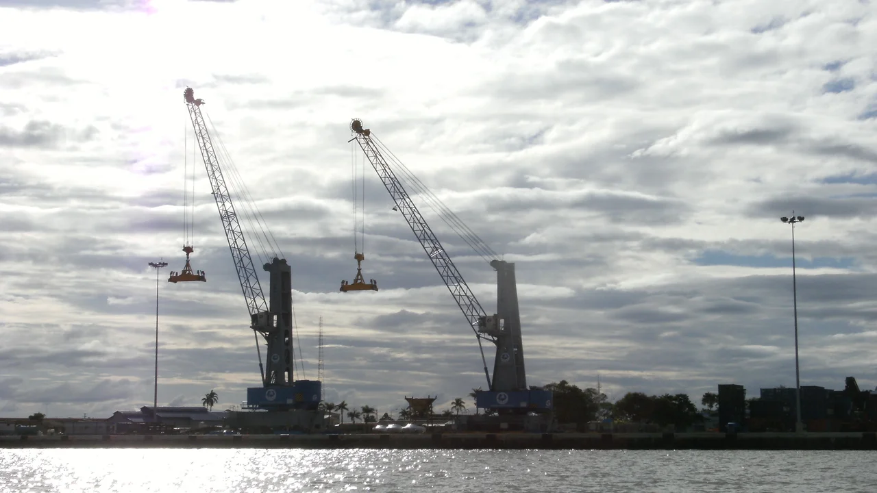 Heavy harbor cranes and container handling equipment towering over the quay at Paramaribo port.