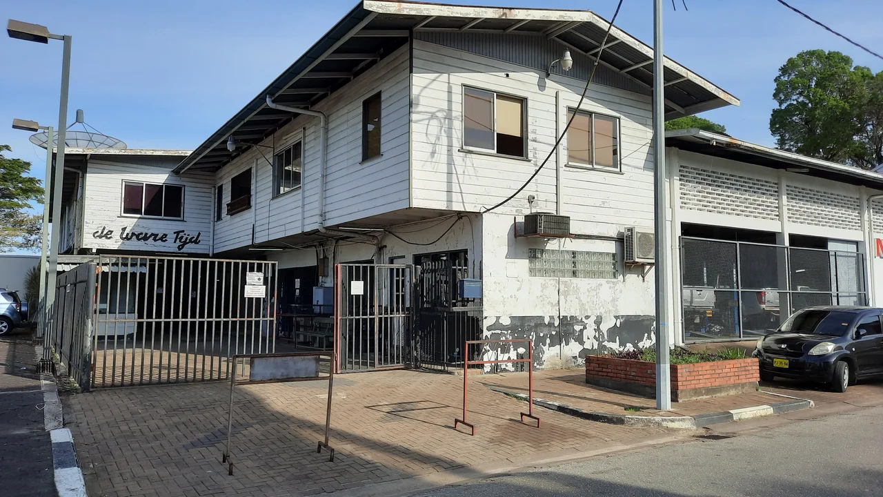 Modern office exterior of De Ware Tijd daily newspaper headquarters on Malebatrumstraat in Paramaribo.