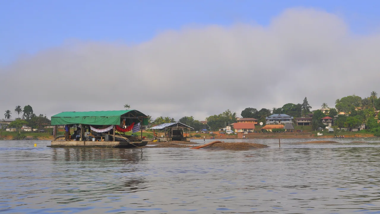 Alluvial gold mining barge operating along the forested waters of the upper Marowijne river basin.
